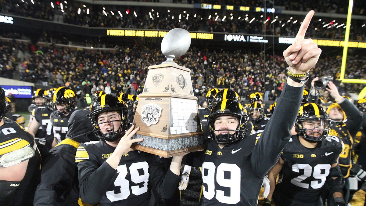 Iowa Hawkeyes players carry a trophy