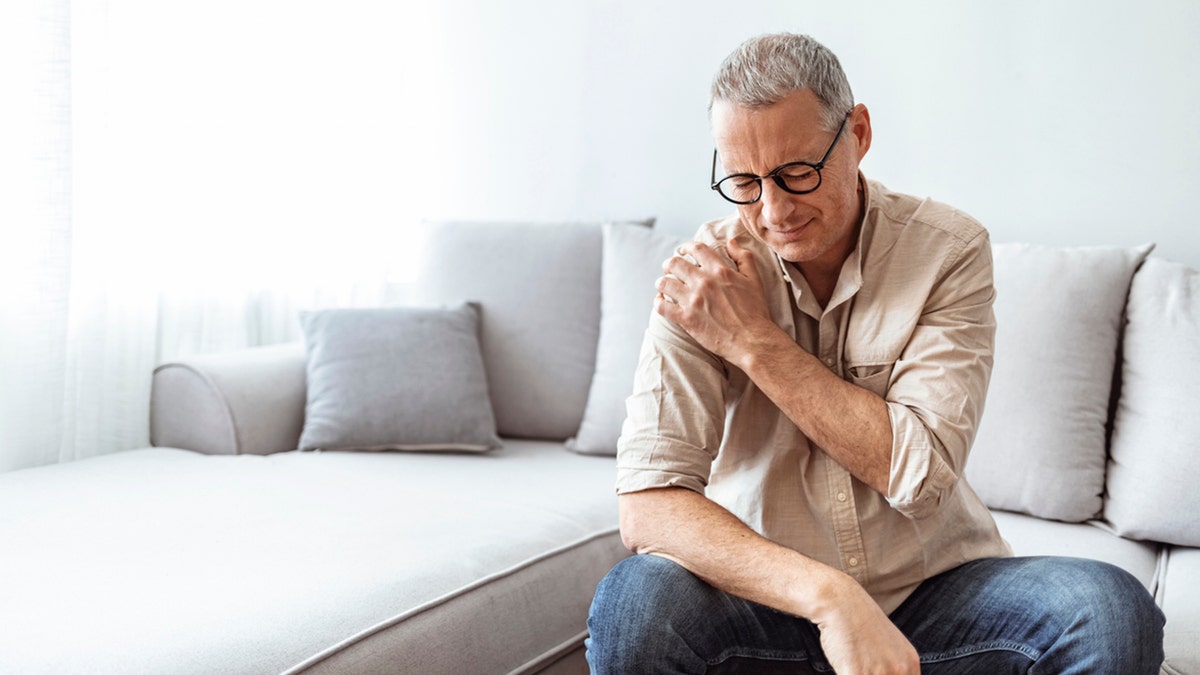 man holding his shoulder in pain