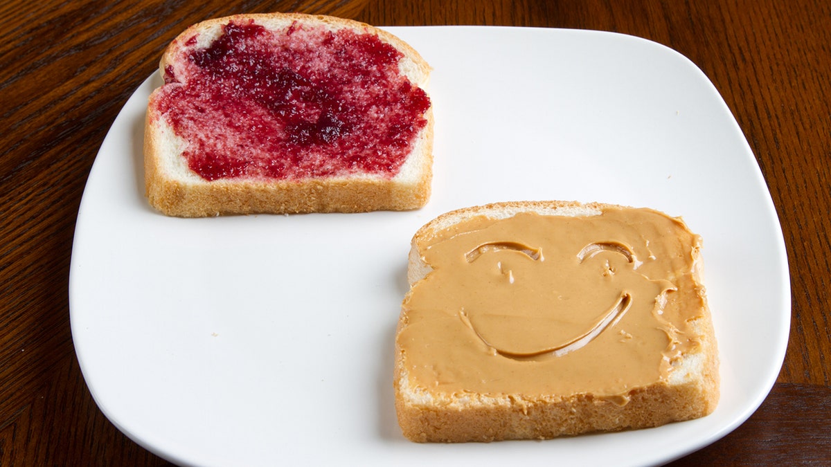 A peanut butter and jelly sandwich with a smile in the peanut butter.