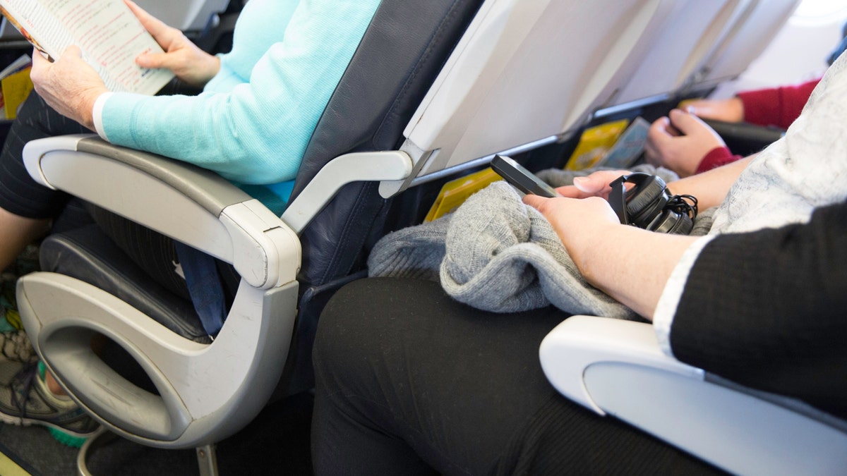 Passengers seated on an airplane are cramped in their seats