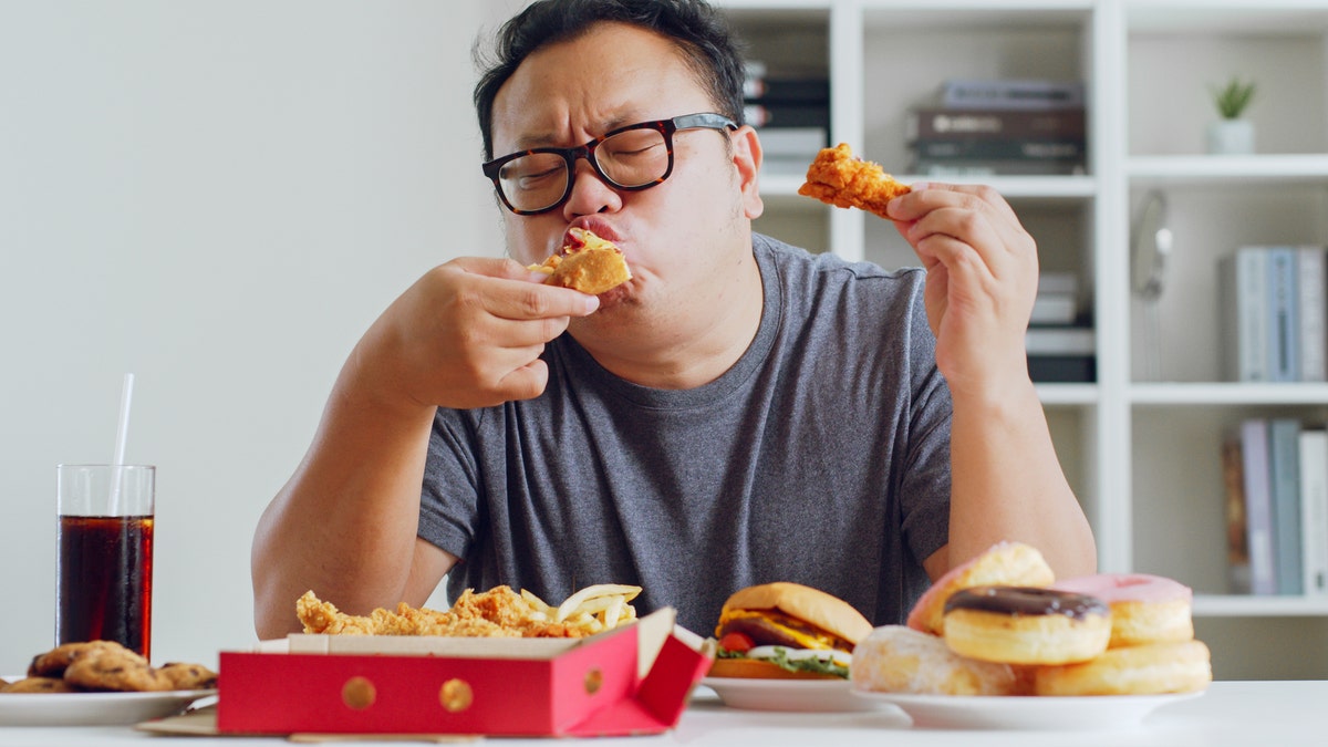 A man enjoys eating unhealthy junk food.