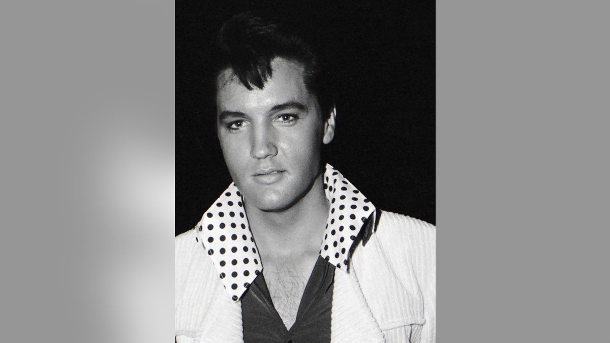 Close-up of Elvis Presley wearing a white jacket with a dotted collar shirt.