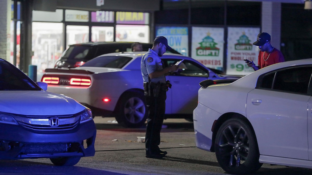 An officer takes a report in the parking lot