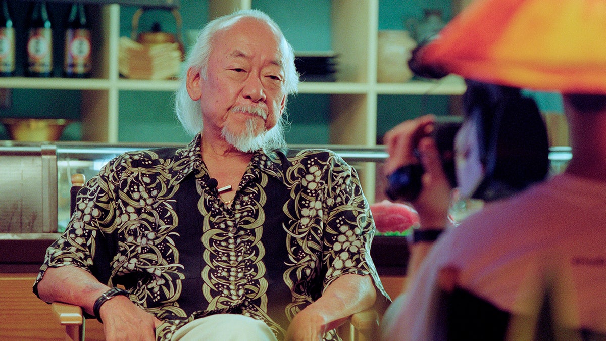 Pat Morita sitting in a chair