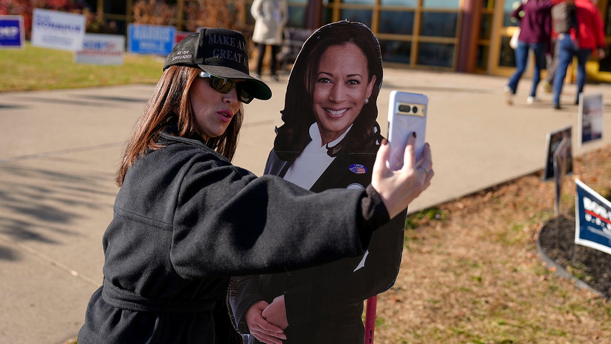 Woman taking photo with Kamala Harris cut out at polling place