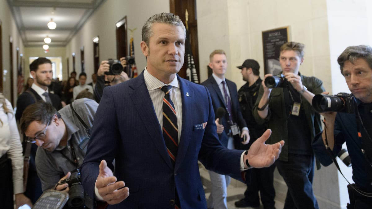 Pete Hegseth berbicara dengan tangan terangkat