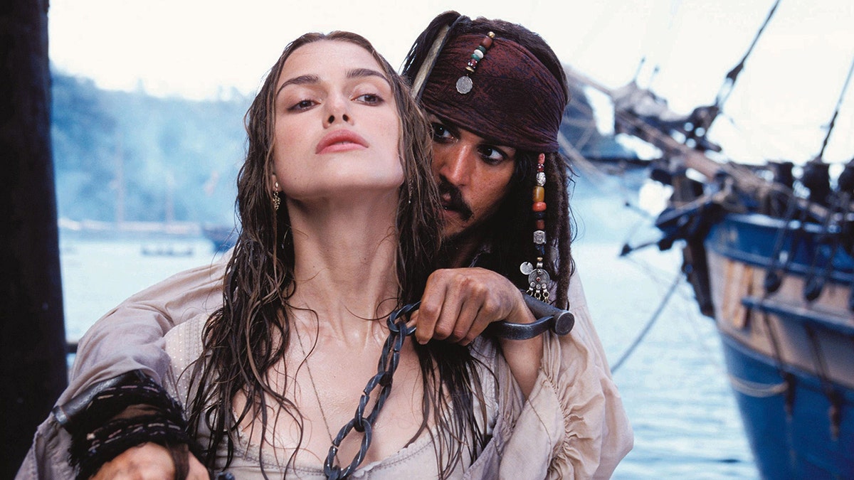 Keira Knightley as Elizabeth Swann looks up slightly while Johnny Depp as Captain Jack Sparrow looks at her from behind