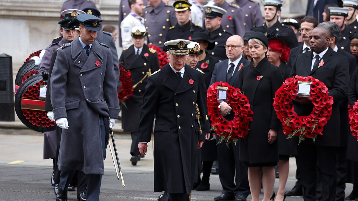 Prince William and Prince Charles walking with a group to lay wreaths