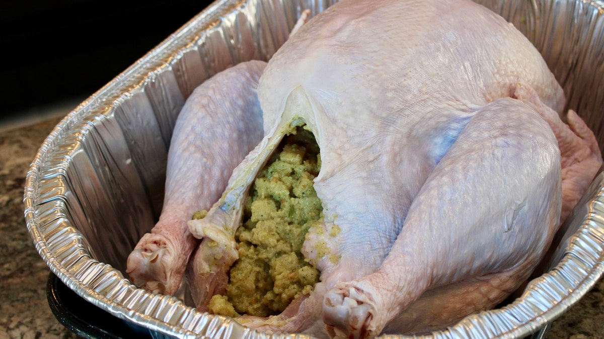 An uncooked turkey is filled with stuffing.