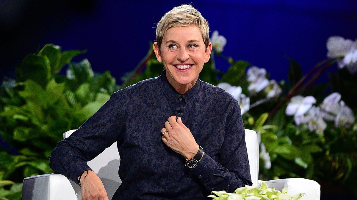 Ellen Degeneres in a button down shirt smiles and looks to her right