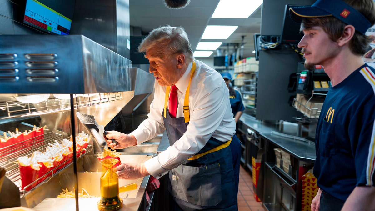 Republican presidential candidate and former President Donald Trump (left) uses a deep fryer as an employee looks on during a visit to a McDonald's in Feasterville-Trevose, Pennsylvania, Sunday, Oct. 20, 2024.