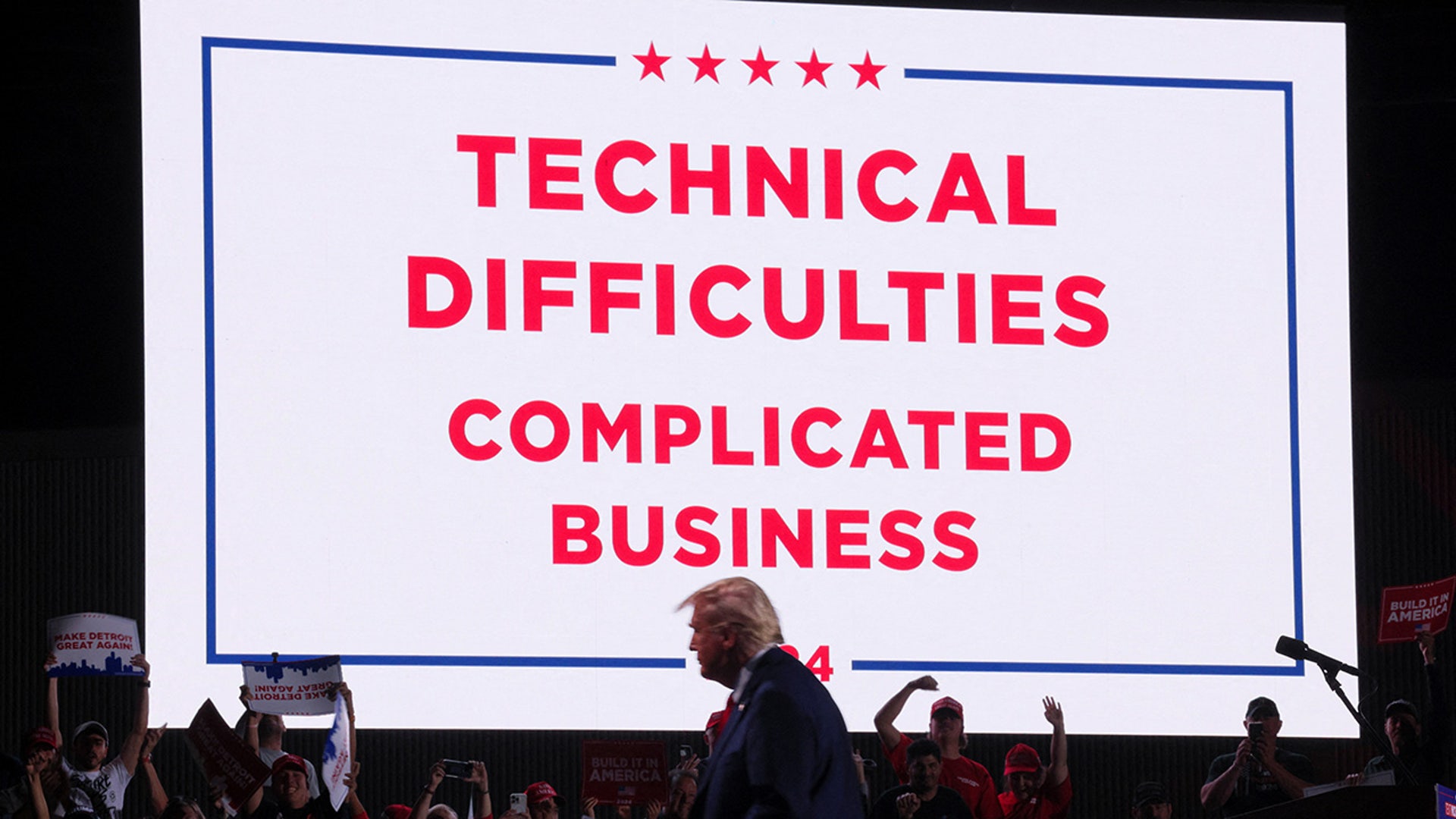 Republican presidential nominee and former U.S. President Donald Trump walks in front of a sign announcing technical difficulties during a rally at Huntington Place