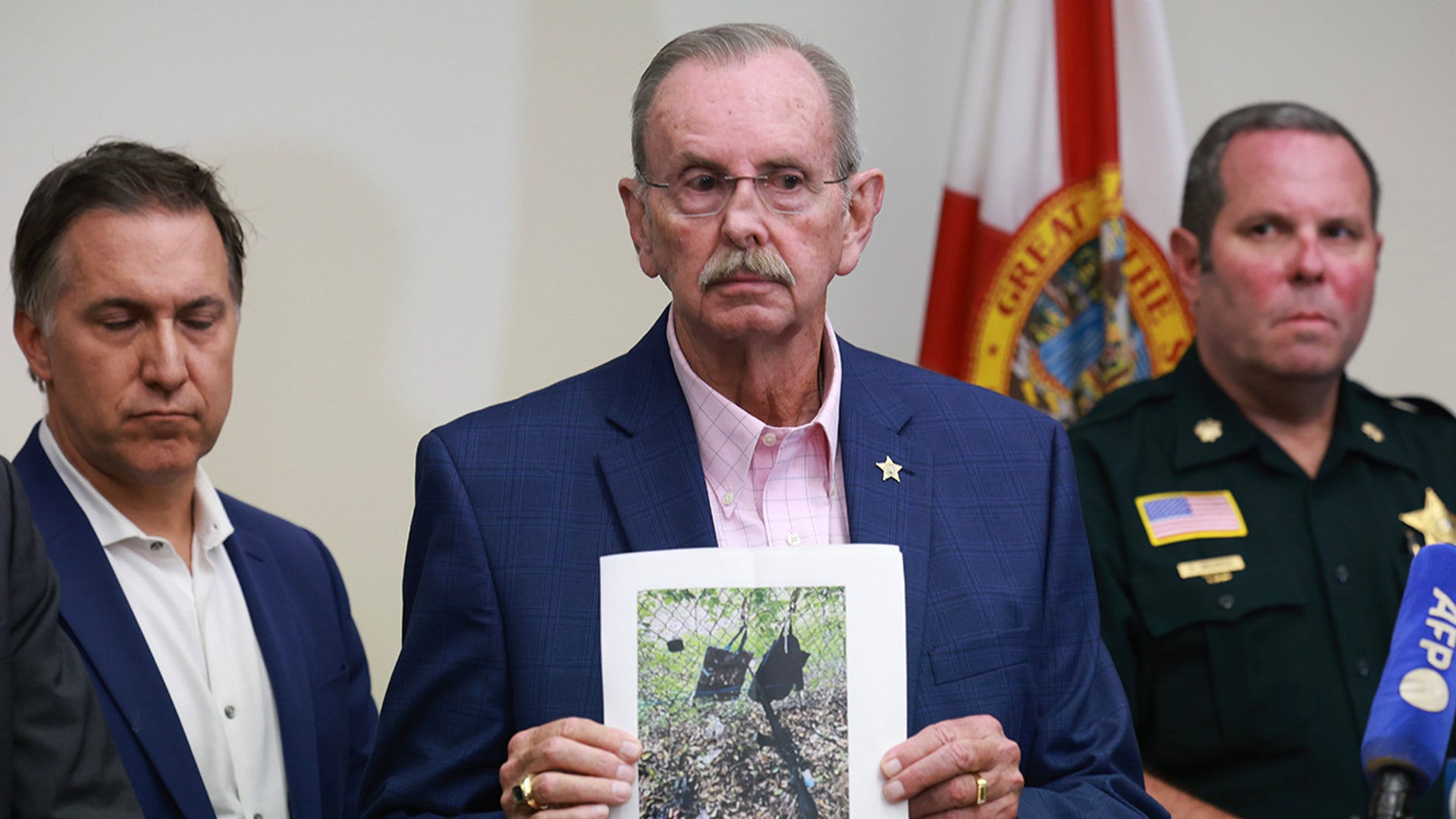 Palm Beach County Sheriff Ric Bradshaw holds a photograph of the rifle and other items found near where a suspect was discovered during a press conference regarding an apparent assassination attempt of former President Donald Trump