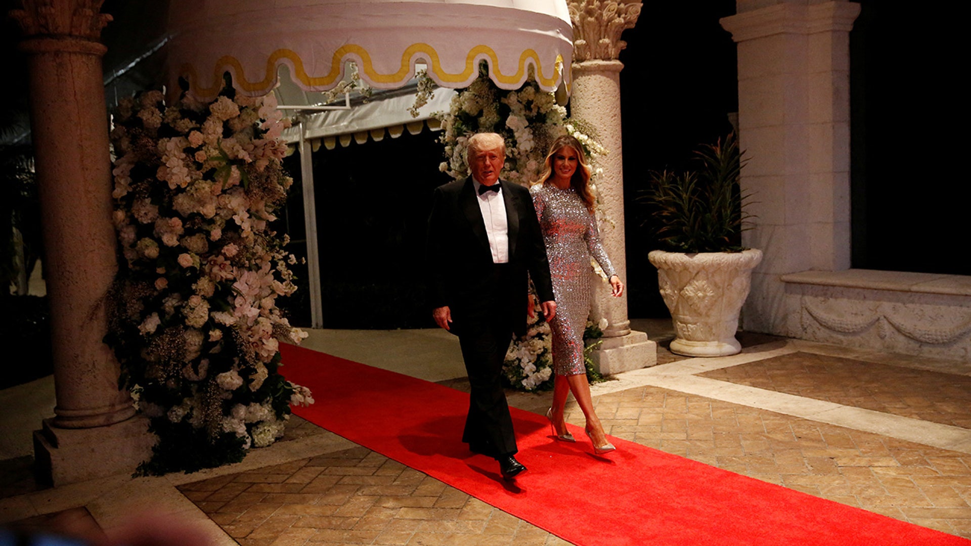 Former President Donald Trump and former first lady Melania Trump walk on the day of their New Year's Eve party at his Mar-a-Lago resort