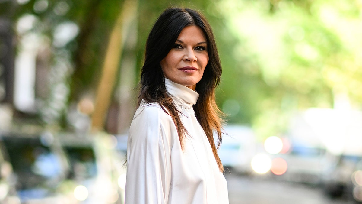 Danielle Vasinova in a white turtleneck looks directly at the camera in New York