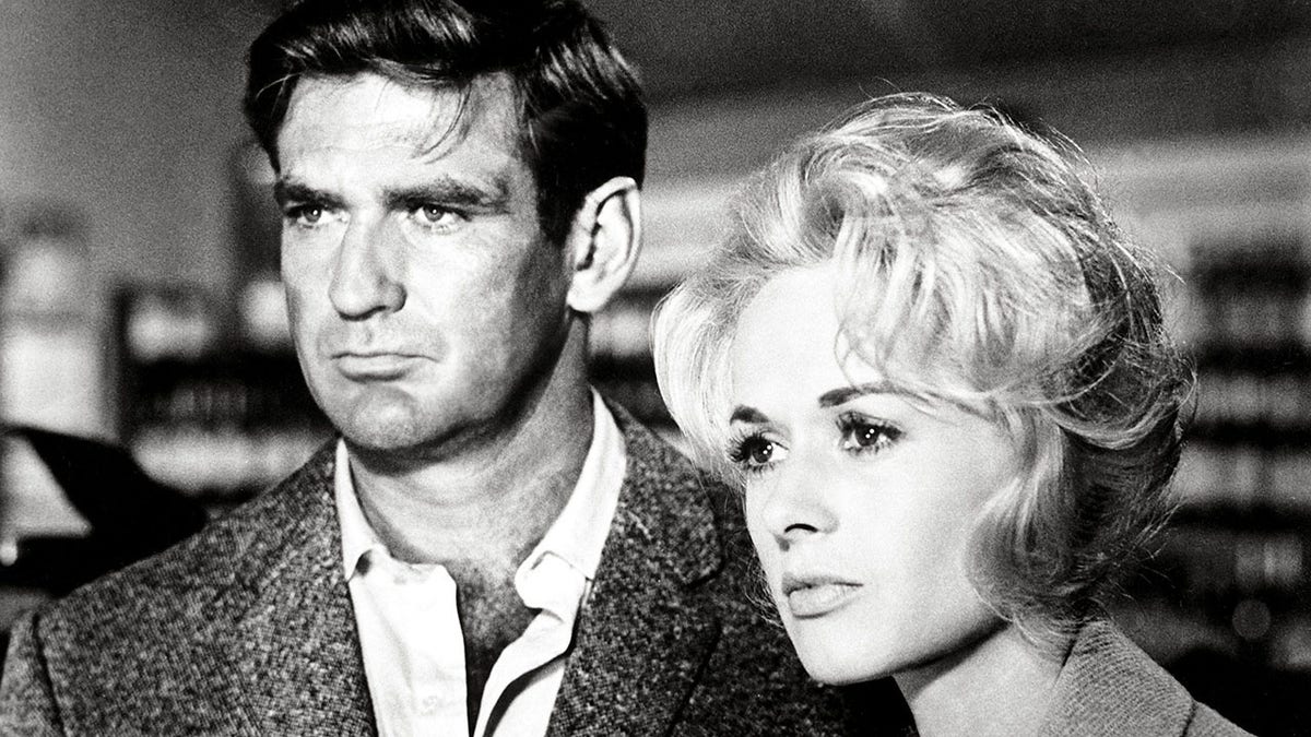 A close-up of Rod Taylor and Tippi Hedren looking pensive in "The Birds."