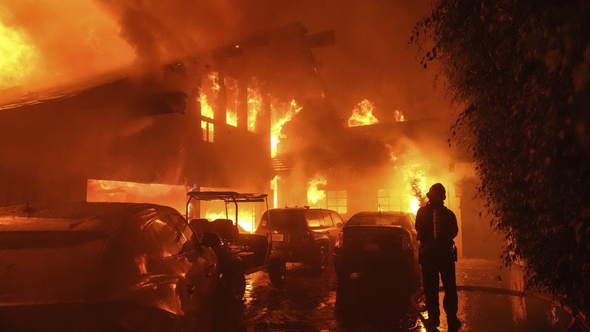 Firefighters spray water on burning house