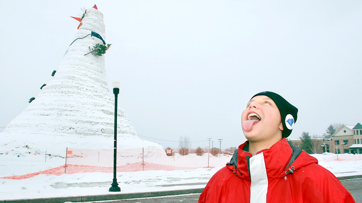 Young boy standing in front of the world's largest snowman 