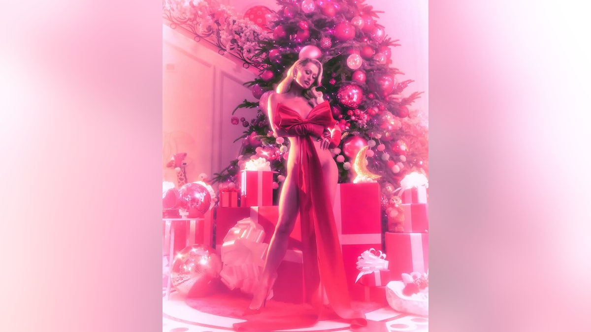 Paris Hilton modeling a giant bow surrounded by presents.