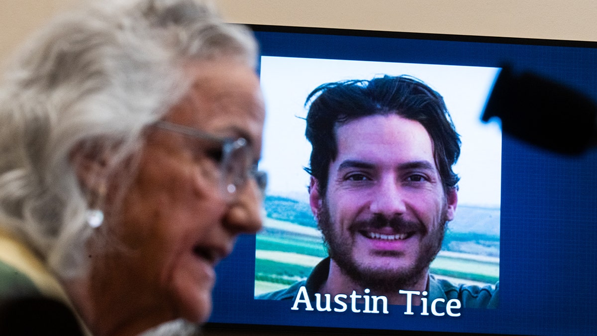 Debra Tice speaks in front of a screen displaying a picture of Austin Tice