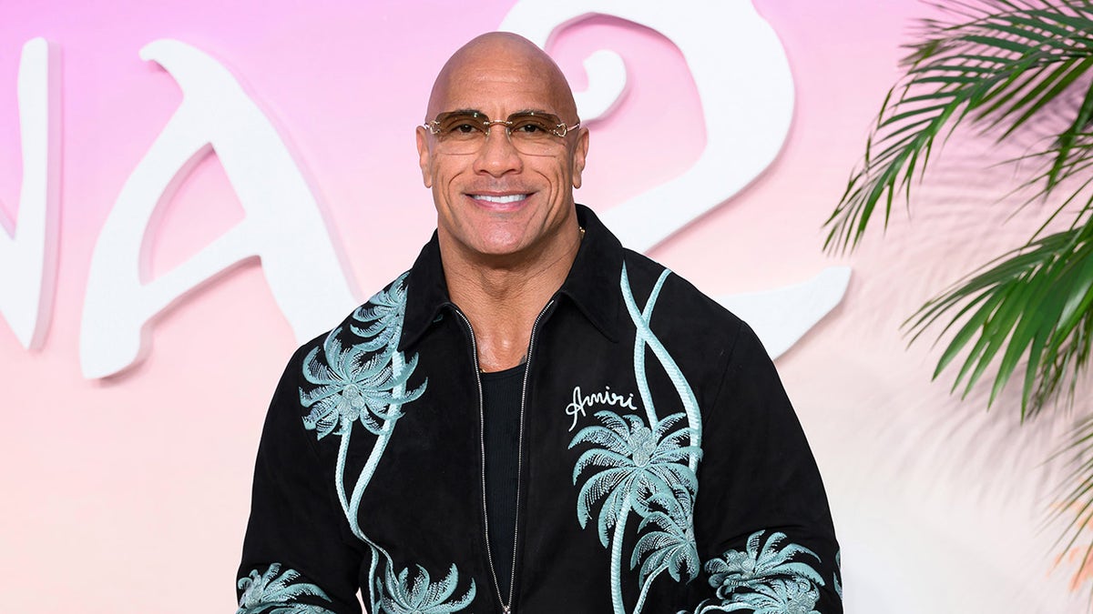 Dwayne "Batu" Johnson mengenakan kemeja hitam dengan motif telapak tangan hijau di karpet merah