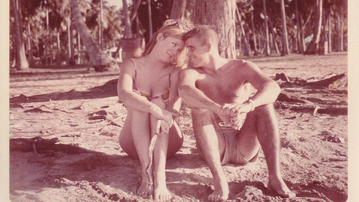 Oliver North fotografiado con su joven esposa en una playa