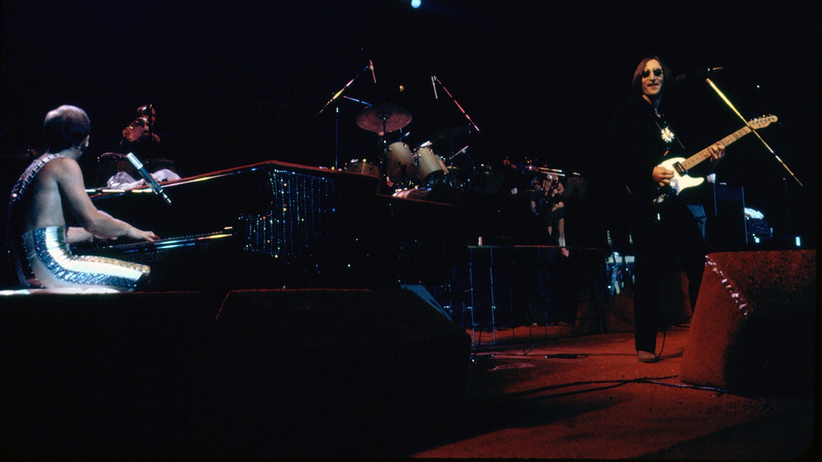 Elton John and John Lennon performing on stage