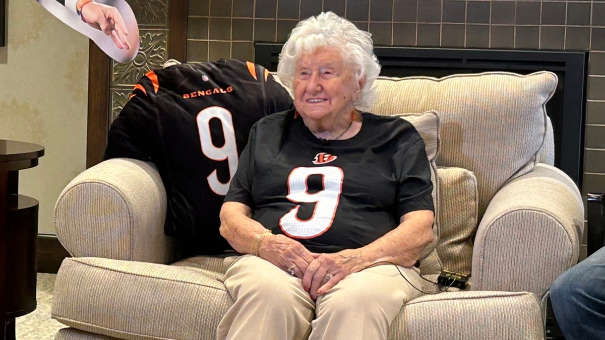 Woman sitting on couch in Joe Burrow jersey.