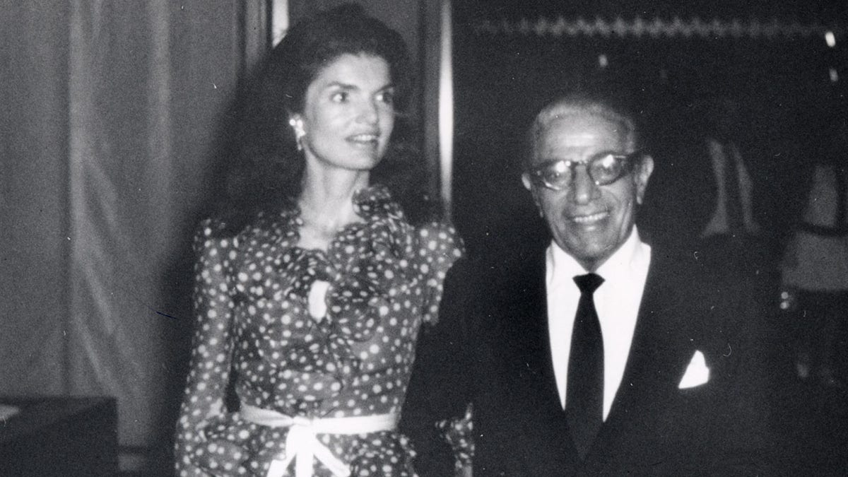 Jackie Kennedy in a polka dot dress with Aristotle Onassis next to her