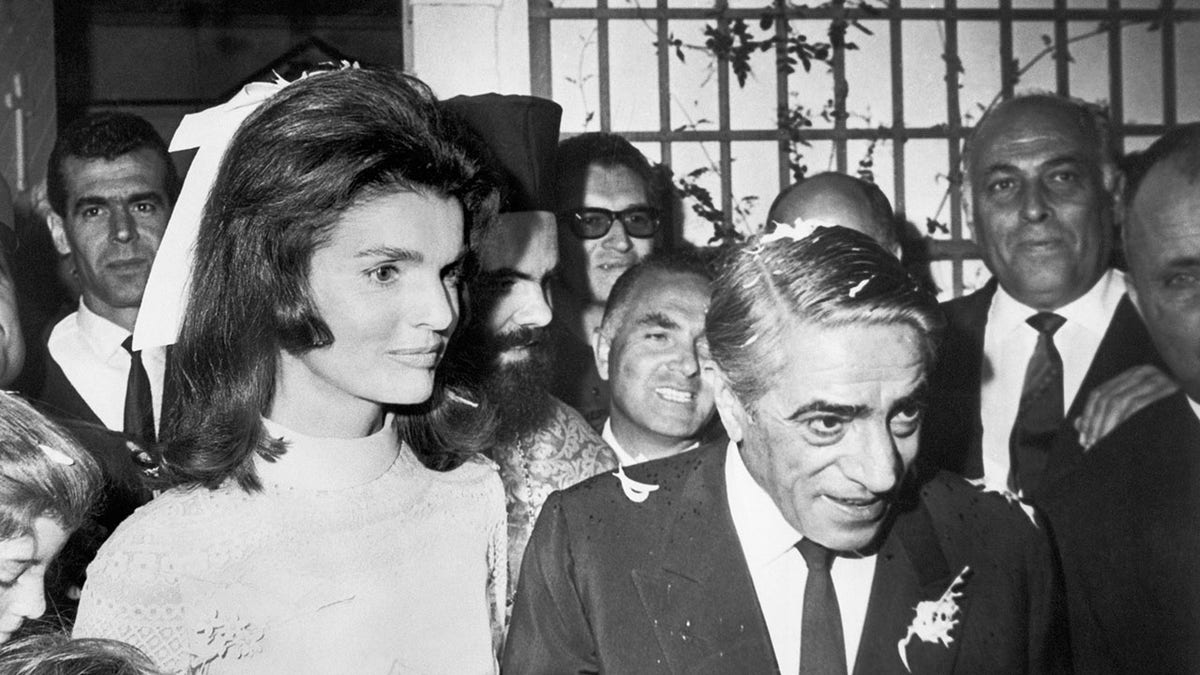 Close-up of Jackie Kennedy and Aristotle Onassis walking among the crowd on their wedding day.