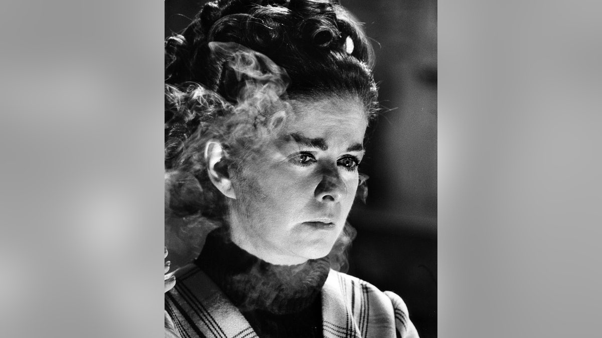Un gros plan de Joan Bennett entourée de fumée.