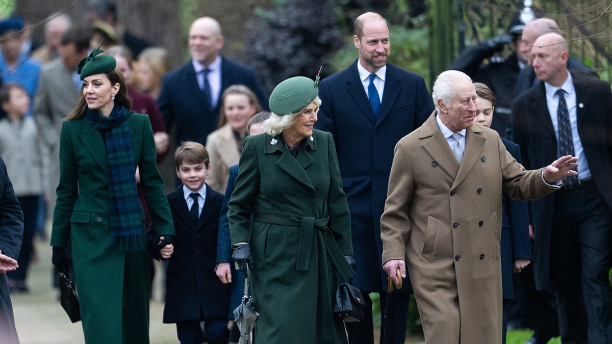 La familia real caminando junta fuera de la iglesia vestida de azul marino y verde a juego.