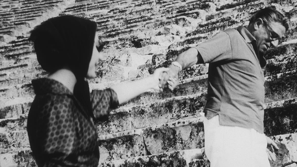 Aristotle Onassis held Maria Callas' hand as they climbed the stairs.