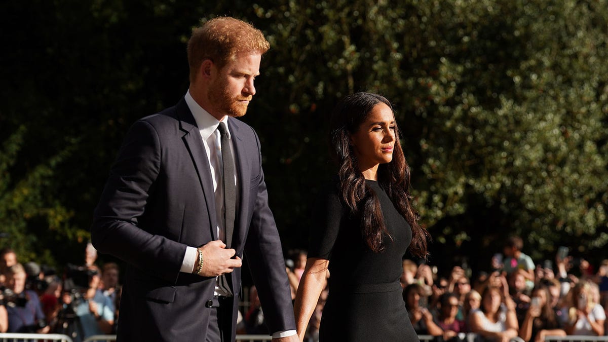 Prince Harry and Meghan Markle look gloomy as they walk in public, dressed in black and held their hands.