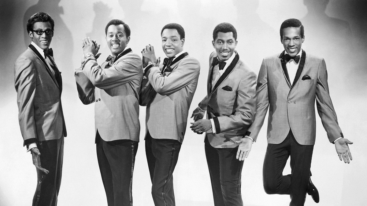 The Temptations in matching suits posing and smiling.