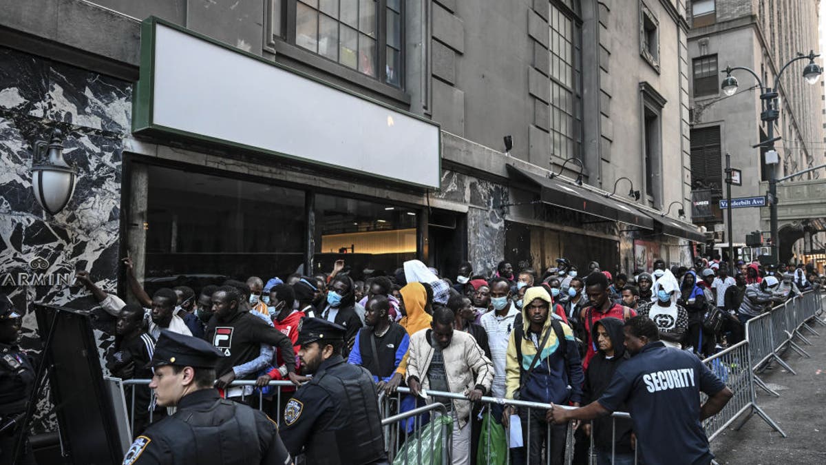 Police officers take security measures as migrants line up outside the Roosevelt Hotel while waiting for placement inside a shelter as asylum seekers camp outside the hotel after the Manhattan relief center is at full capacity in New York City on Aug. 2, 2023.