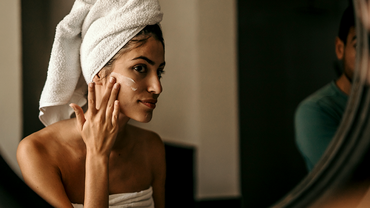 a woman puts moisturizer on her face