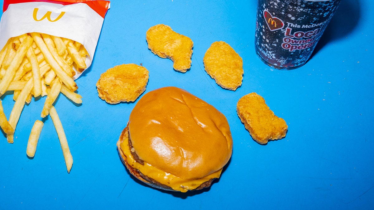 A cheeseburger with four peanuts on it is arranged. Each nuggets is in icon shape.