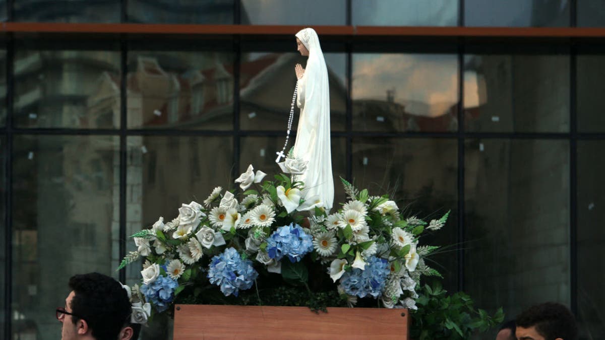 Lebanese Christian Syriac Catholic scouts hold a statue of the Virgin Mary during a procession marking the month of the Virgin Mary in a Christian square in Beirut on May 27, 2016. The Syriac Catholic Church is part of the See of Antioch and extends from the back. on the origins of Christianity in the Levant. 