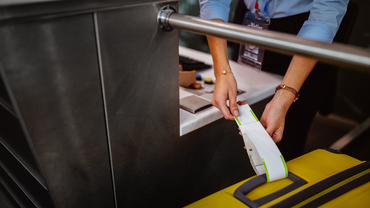 Airport check-in counter employee attaching tag on luggage