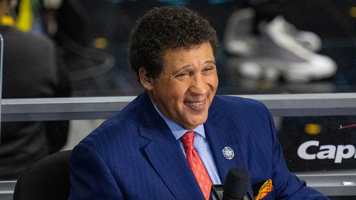 Greg Gumbel looks on