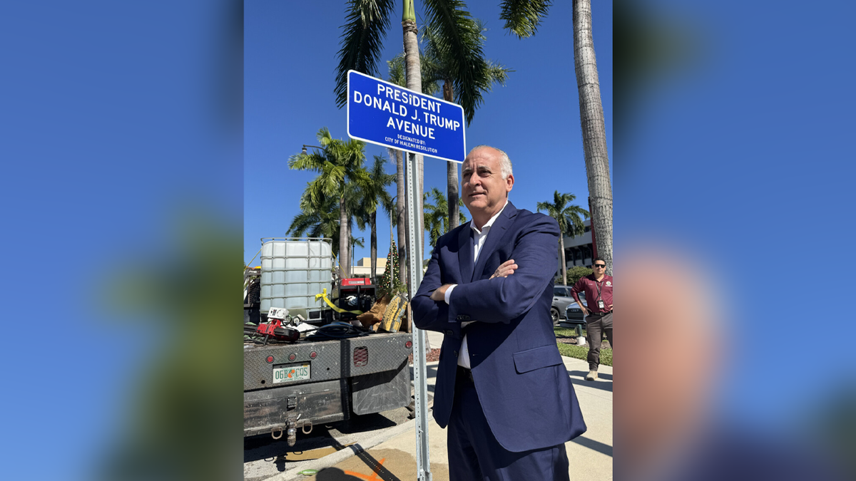 Hialeah Mayor Esteban "Steve" Bovo poses in front of a Donald J. Trump Avenue sign