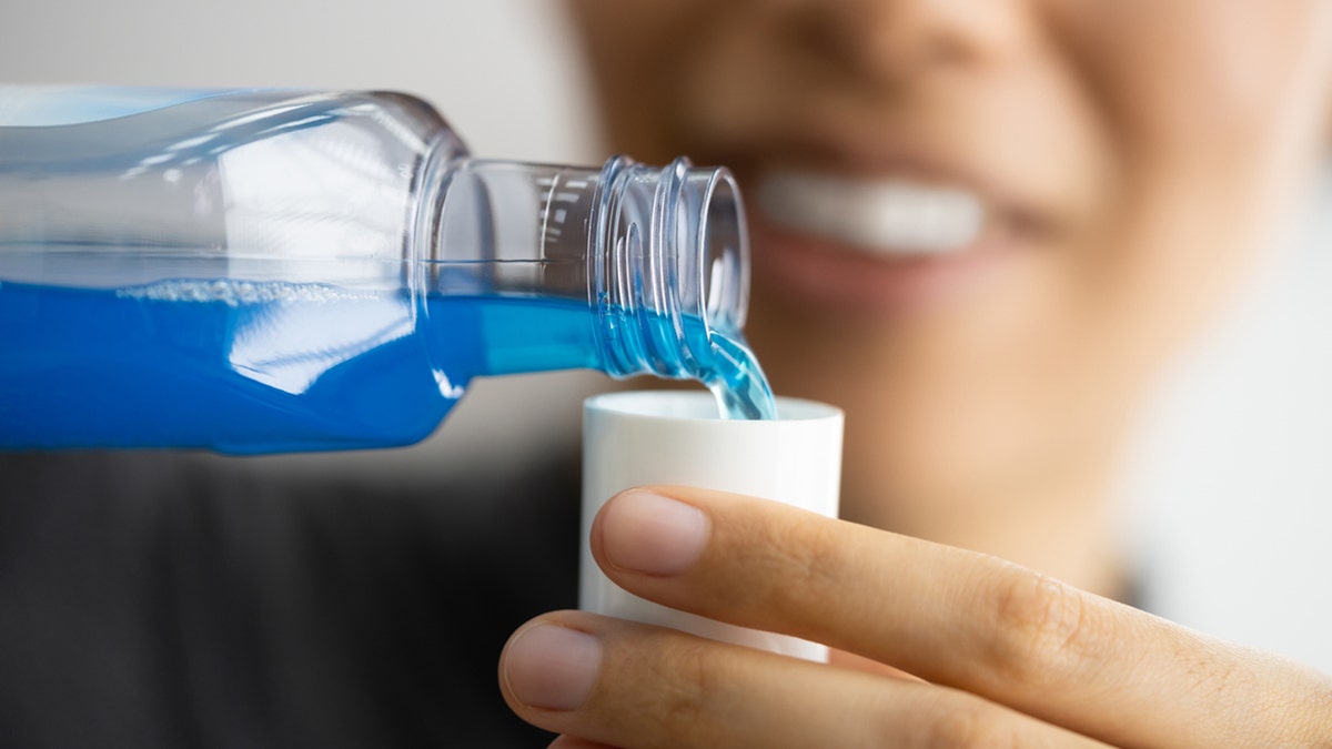 person pours mouthwash into cup