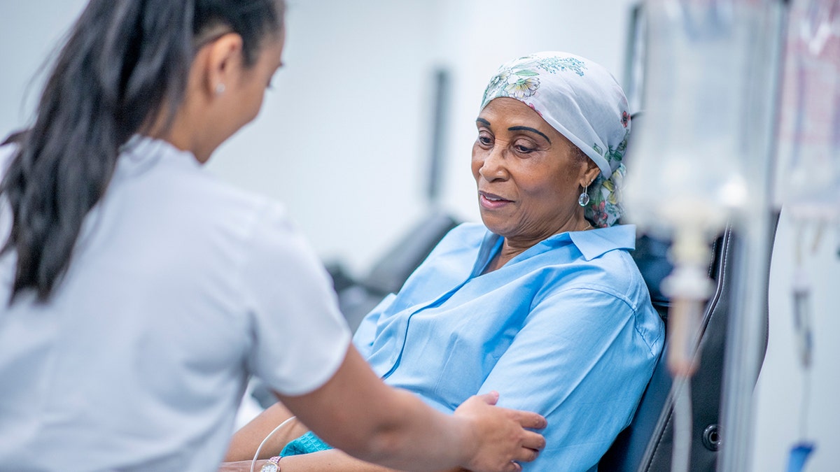 Woman wearing head scarf recovers from chemotherapy treatment in hospital