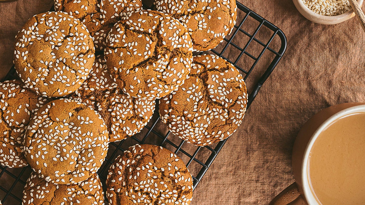 Sesame ginger snap cookies cooling on a rack.