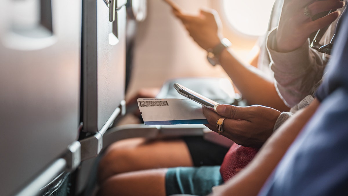 Passenger sits in the middle seat on an airplane.