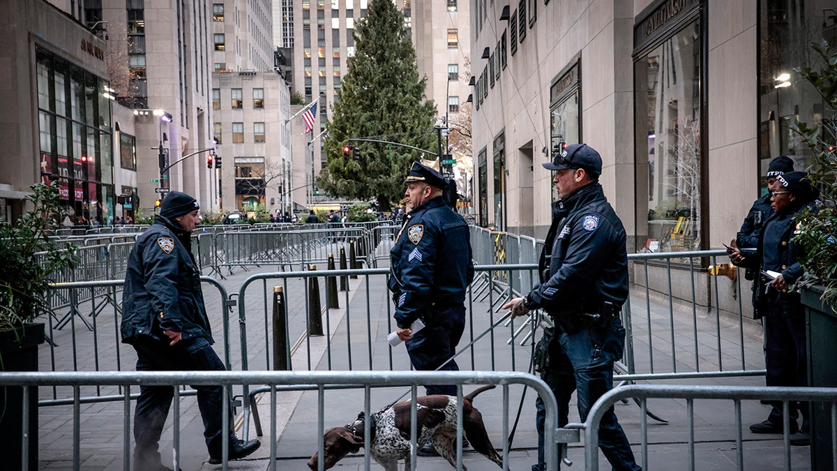 NYPD walks through barriers and a dog outside Rockefeller Plaza before the tree lighting