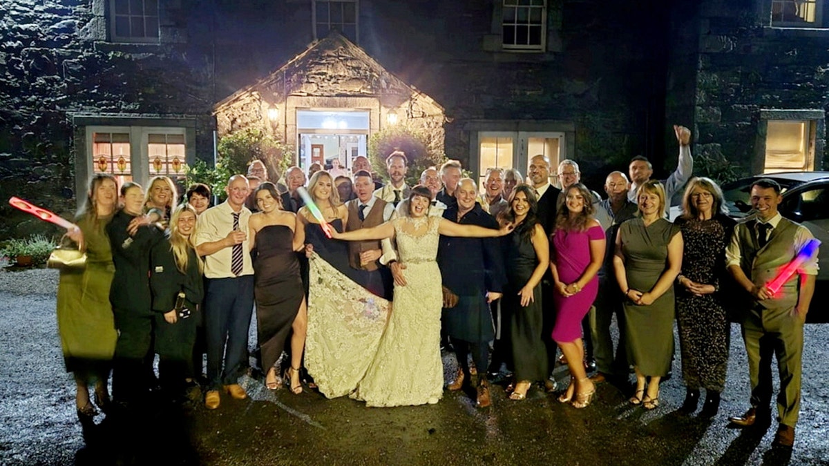 Wayne and Sarah Marshall pose for a photograph with friends and family on their wedding day.