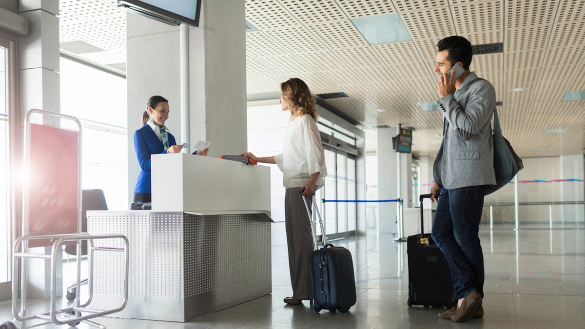 pareja en la cola con el agente de la puerta de embarque en el aeropuerto