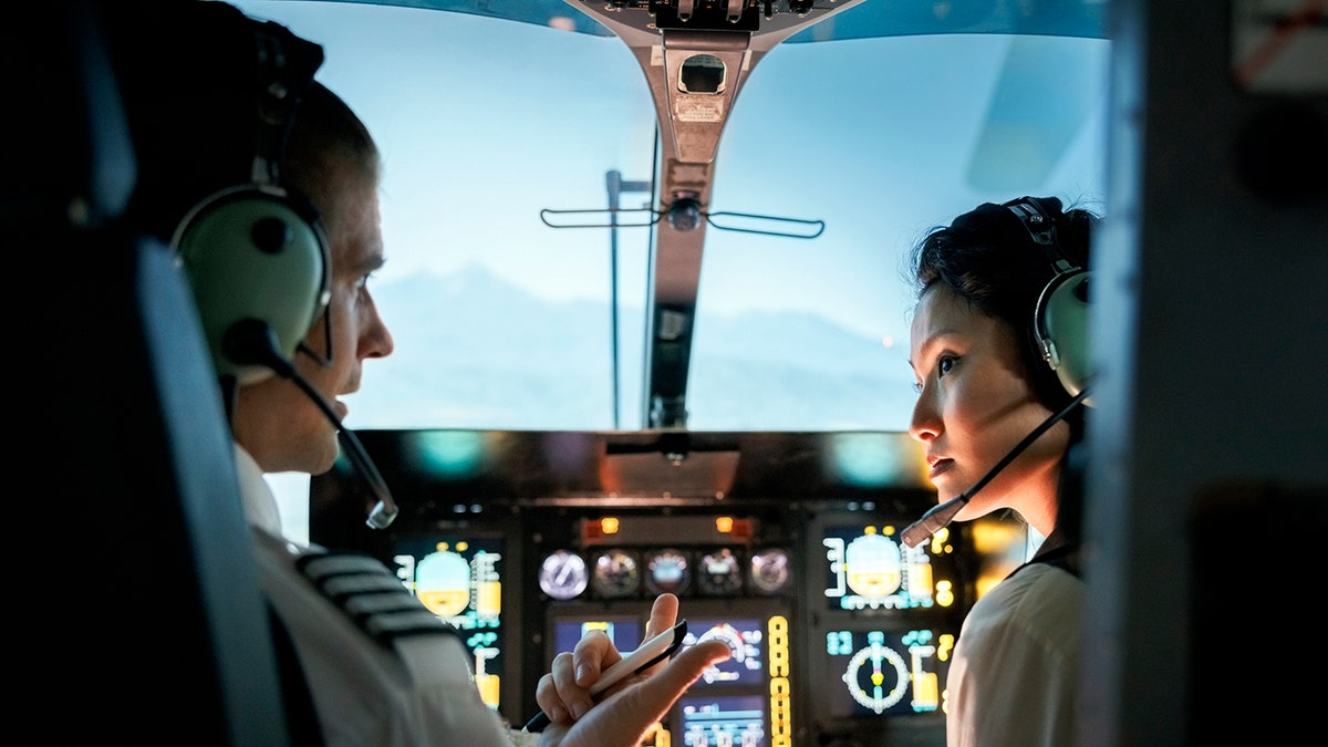 pilots talking through headsets on plane